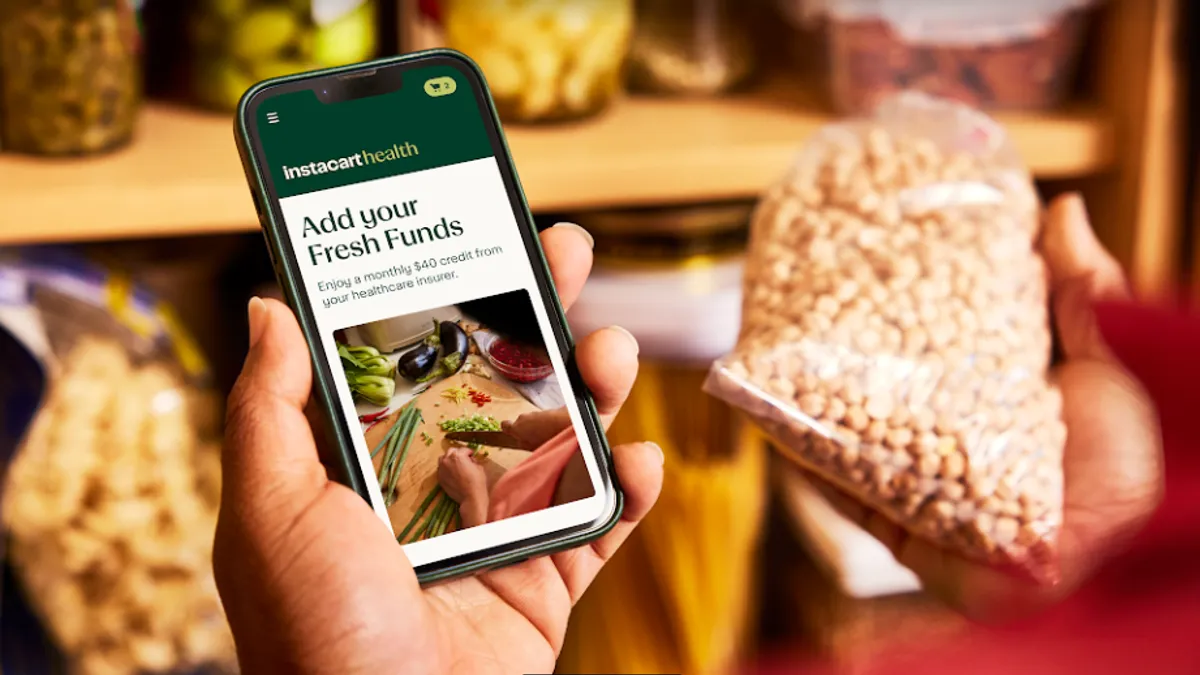 A hand holding a phone that says Instacart Health on the screen.