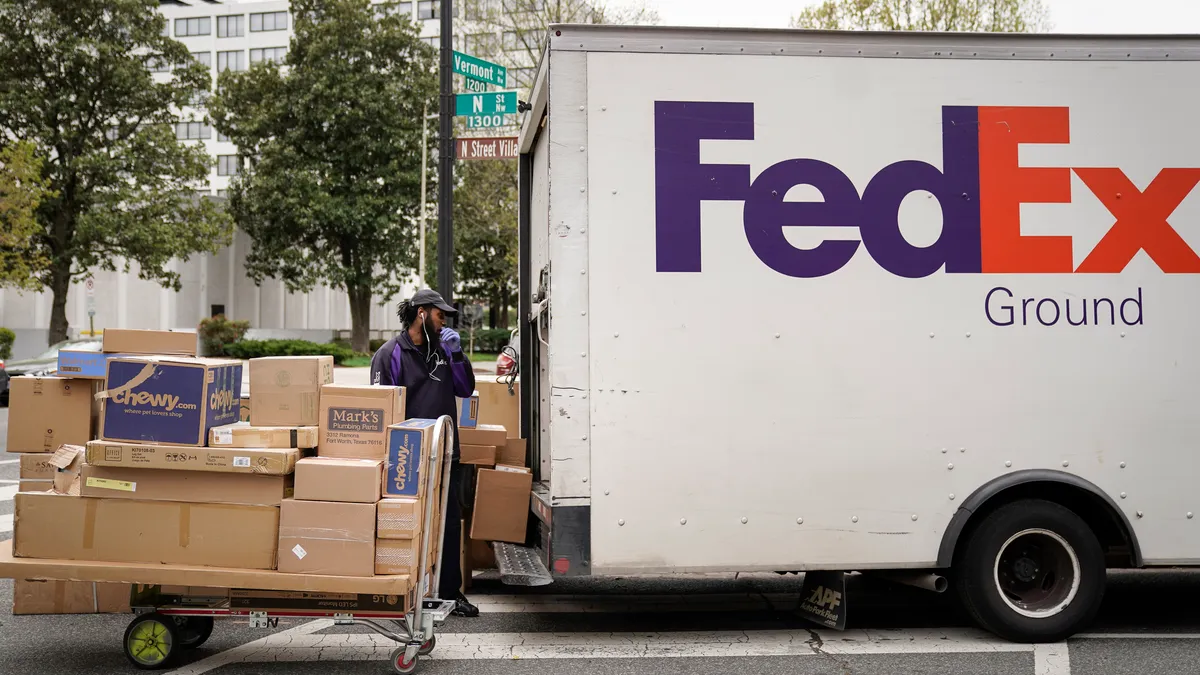 A FedEx worker unloads packages from his delivery truck