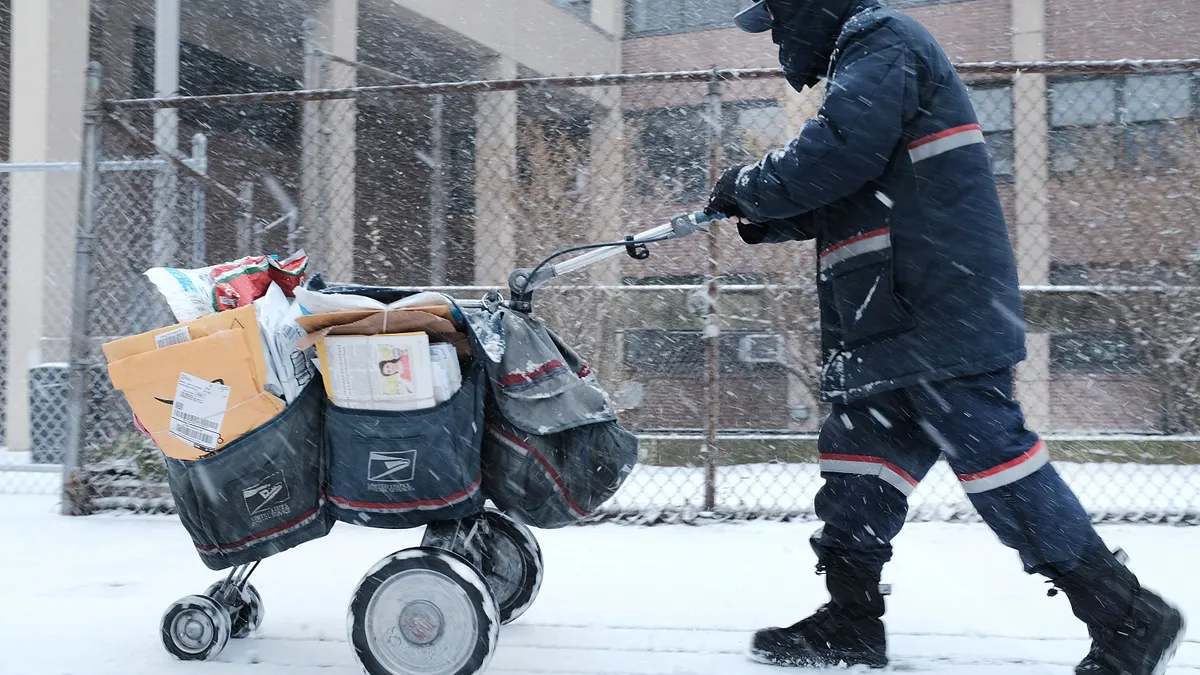 A mail carrier walks through the snow on March 21, 2018 in the Brooklyn borough of New York City.