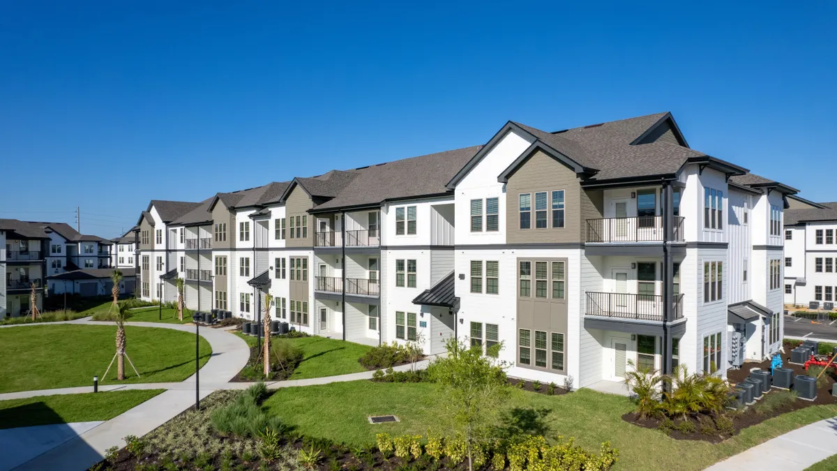 White three-story apartment buildings with black roof.