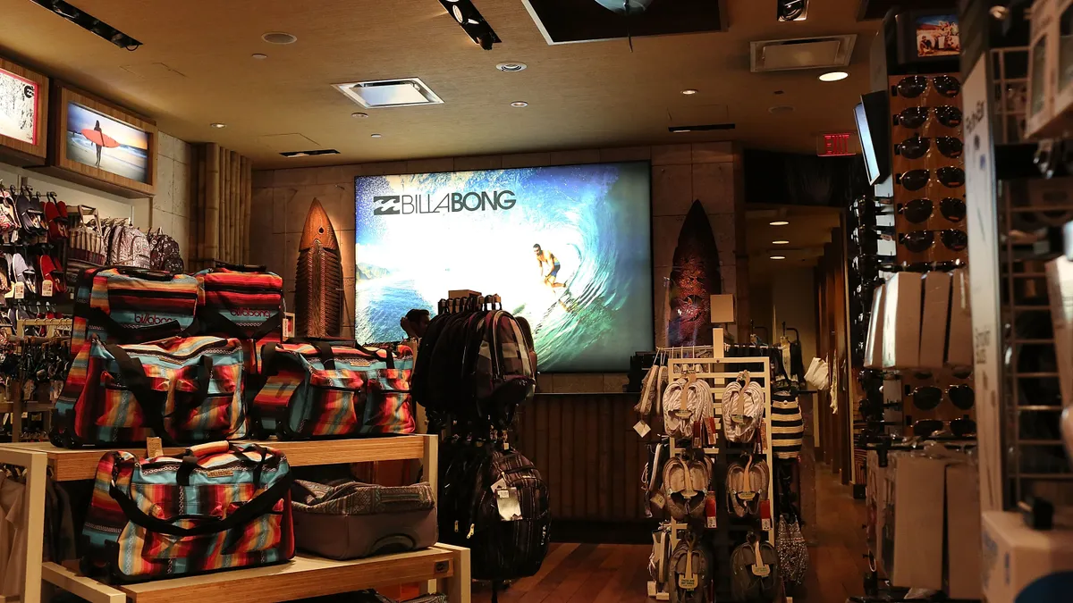 The interior of a Billabong store is pictured, featuring displays of bags, backpacks, shoes and sunglasses.