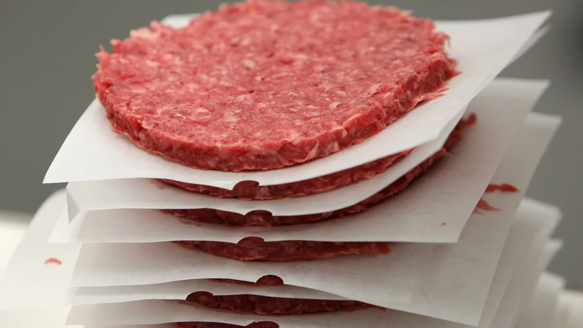 Ground beef patties move on a conveyor belt.