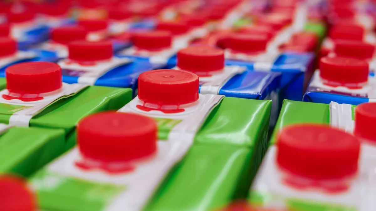 Juice cartons with red screw cap in supermarket shelf.