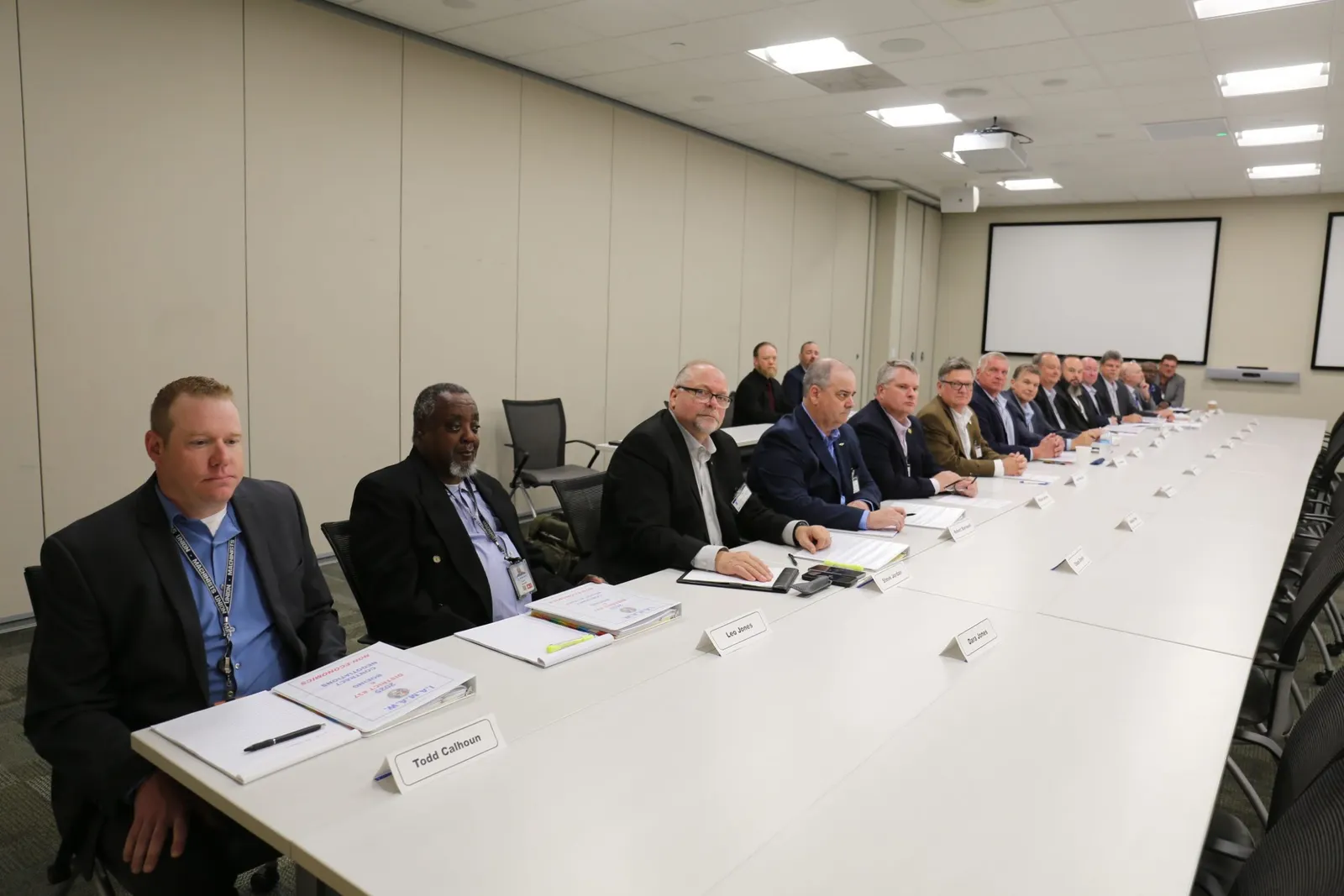 17 people in blazers at a long table facing right.