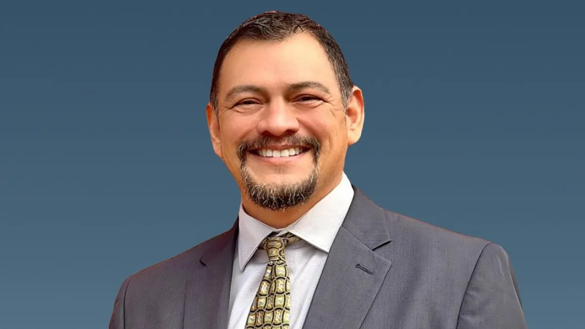 This is a headshot of Kevin Sotomayor, principal of Isaac Middle School in Phoenix. He is standing against a blue background.