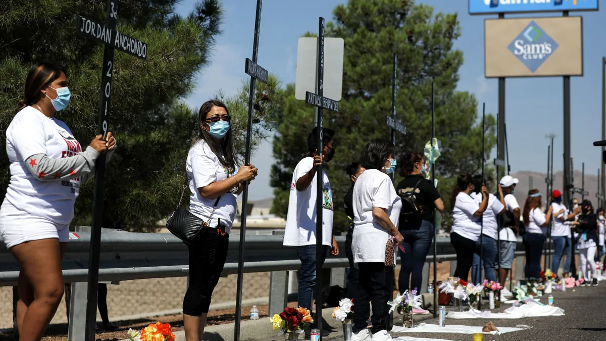 People hold crosses in a parking lot with a Walmart sign overhead.