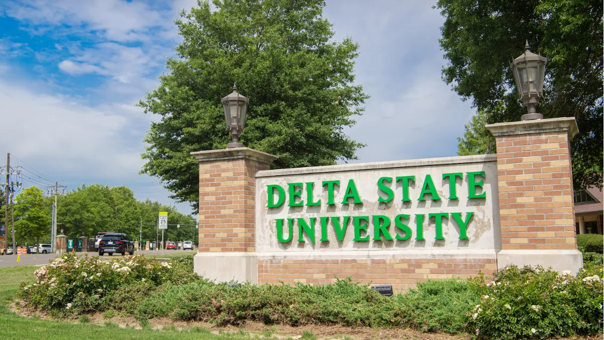 Delta State University sign surrounded by lawn and foliage.