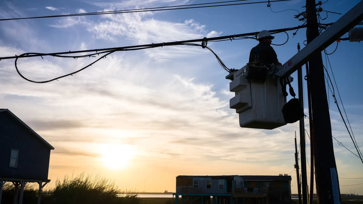 Silhouette of an electrical worker repairing a power line following Hurricane Beryl.