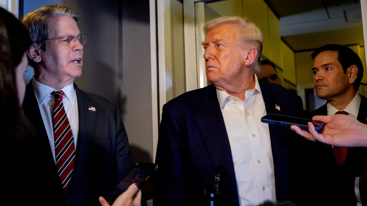 U.S. Treasury Secretary Scott Bessent speaks to reporters next to President Donald Trump and Secretary of State Marco Rubio on Air Force One on Oct. 27, 2025.