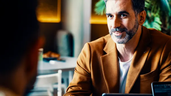 Businessperson listening to colleague in meeting at a table.