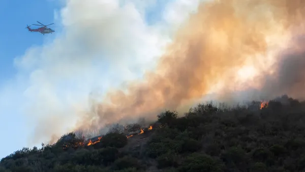 A firefighting helicopter flies over a wildfire