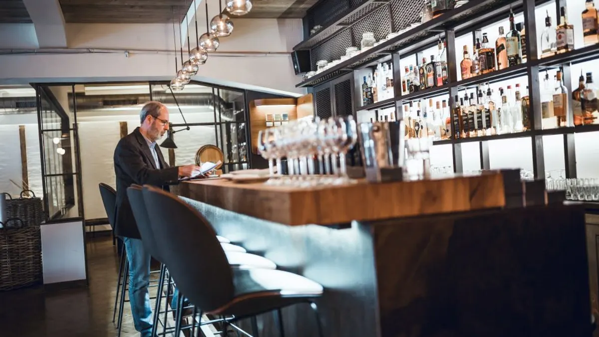 A man stands at a bar checking out.