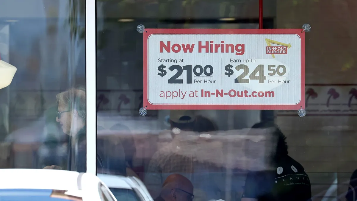 A sign posted on an In-N-Out restaurant advertises a $21 starting hourly wage, with opportunities to earn up to $24.50.