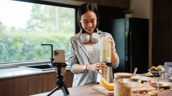 Cheerful influencer filming herself in a cozy kitchen, making a healthy smoothie while sharing an easy-to-follow recipe with her followers.