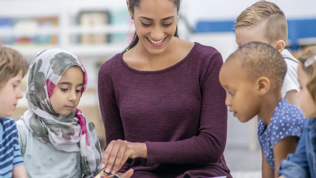Children sat around their teacher reading a book