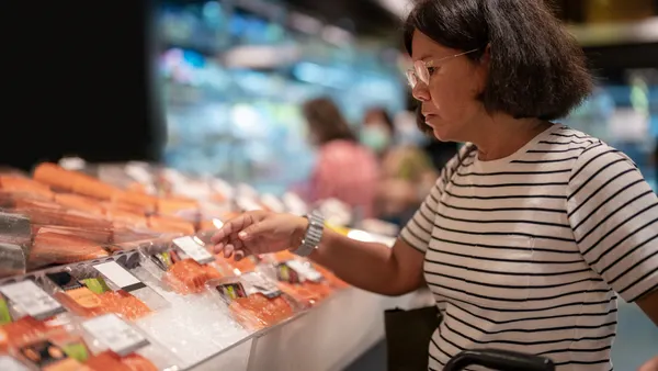 Woman choosing fresh fish at seafood aisle in the supermarket