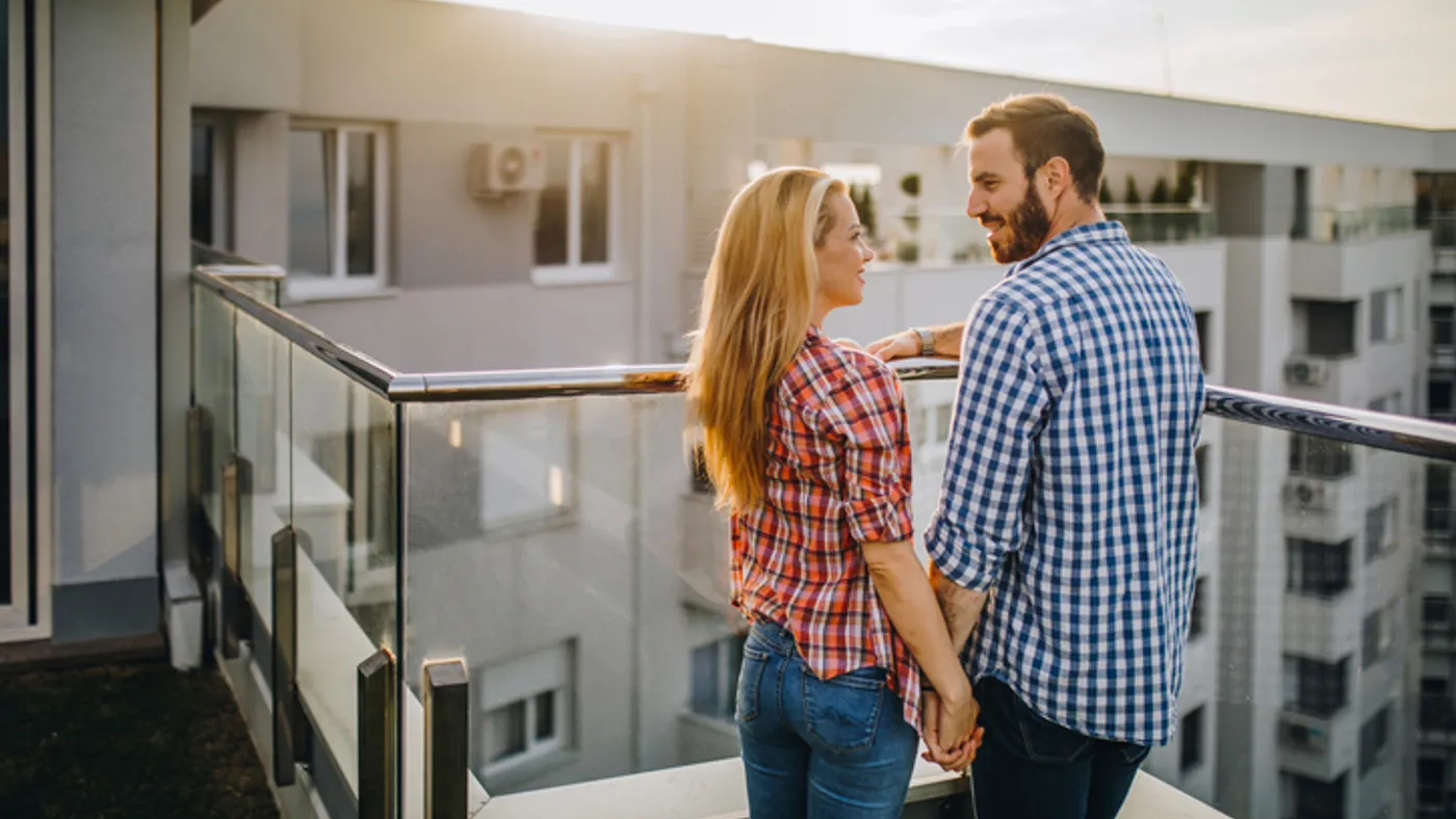 a couple looks out over an apartment balcony