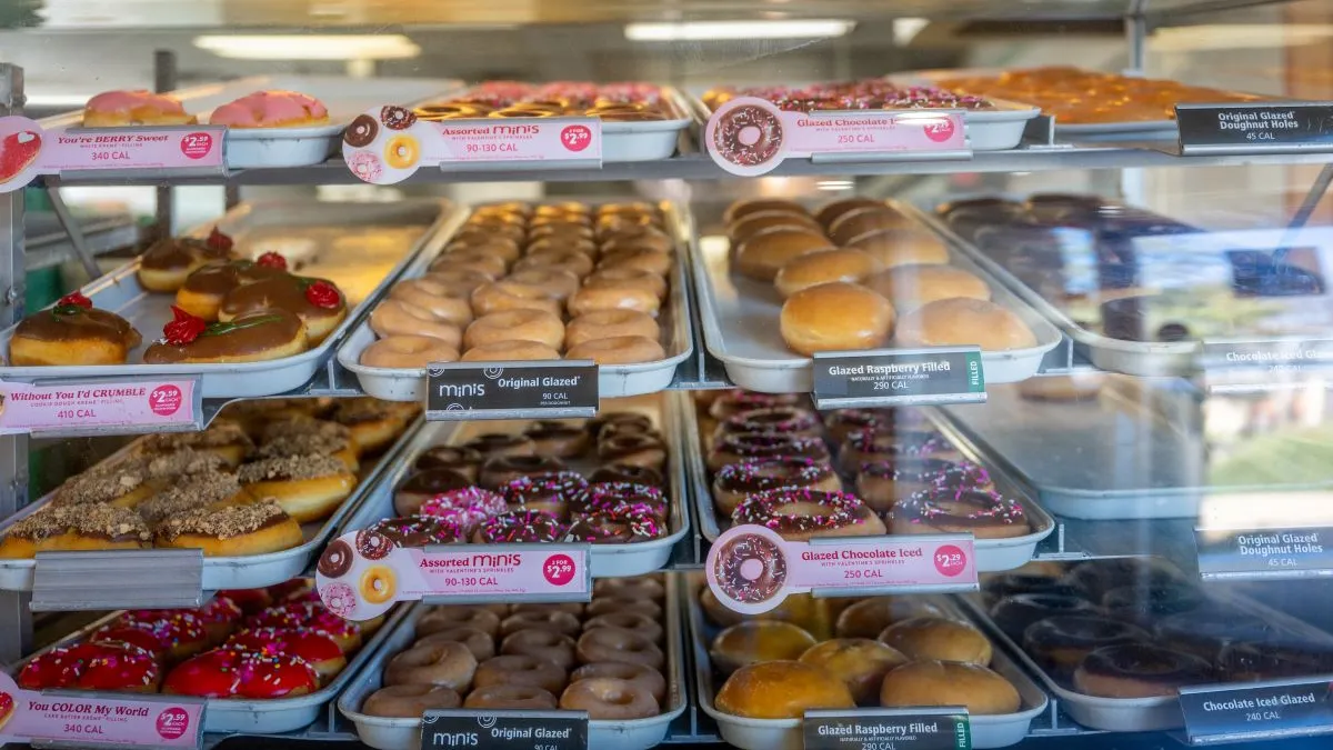 An image of various doughnuts from Krispy Kreme behind a bakery counter.