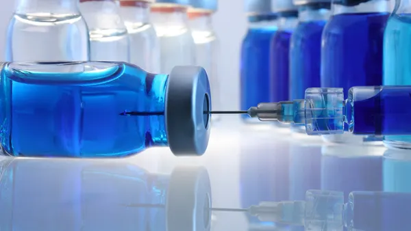 Laboratory bottles with blue content and a syringe