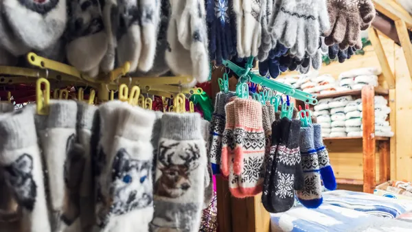 A variety of colorful and warm knitted gloves and mittens are on display at a market stall. The gloves and mittens are made from wool and feature various patterns and designs.