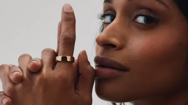 A person wears a ring on their pointer finger while holding their hands close to their face.