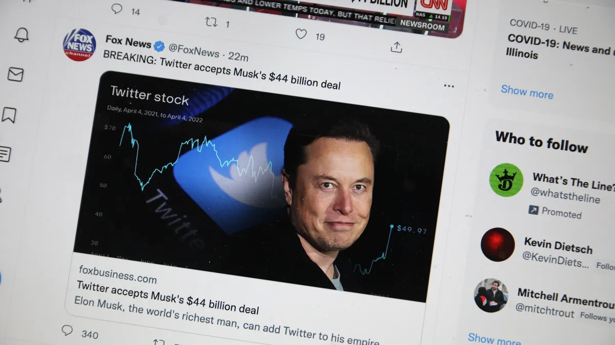 Image of Twitter feed on computer showing Elon Musk's face and a headline about this purchase of the the company.