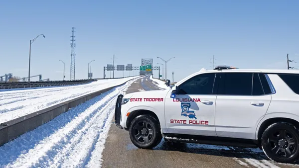 A Louisiana State Police SUV blocks off traffic on a bridge that's covered in snow in one direction.