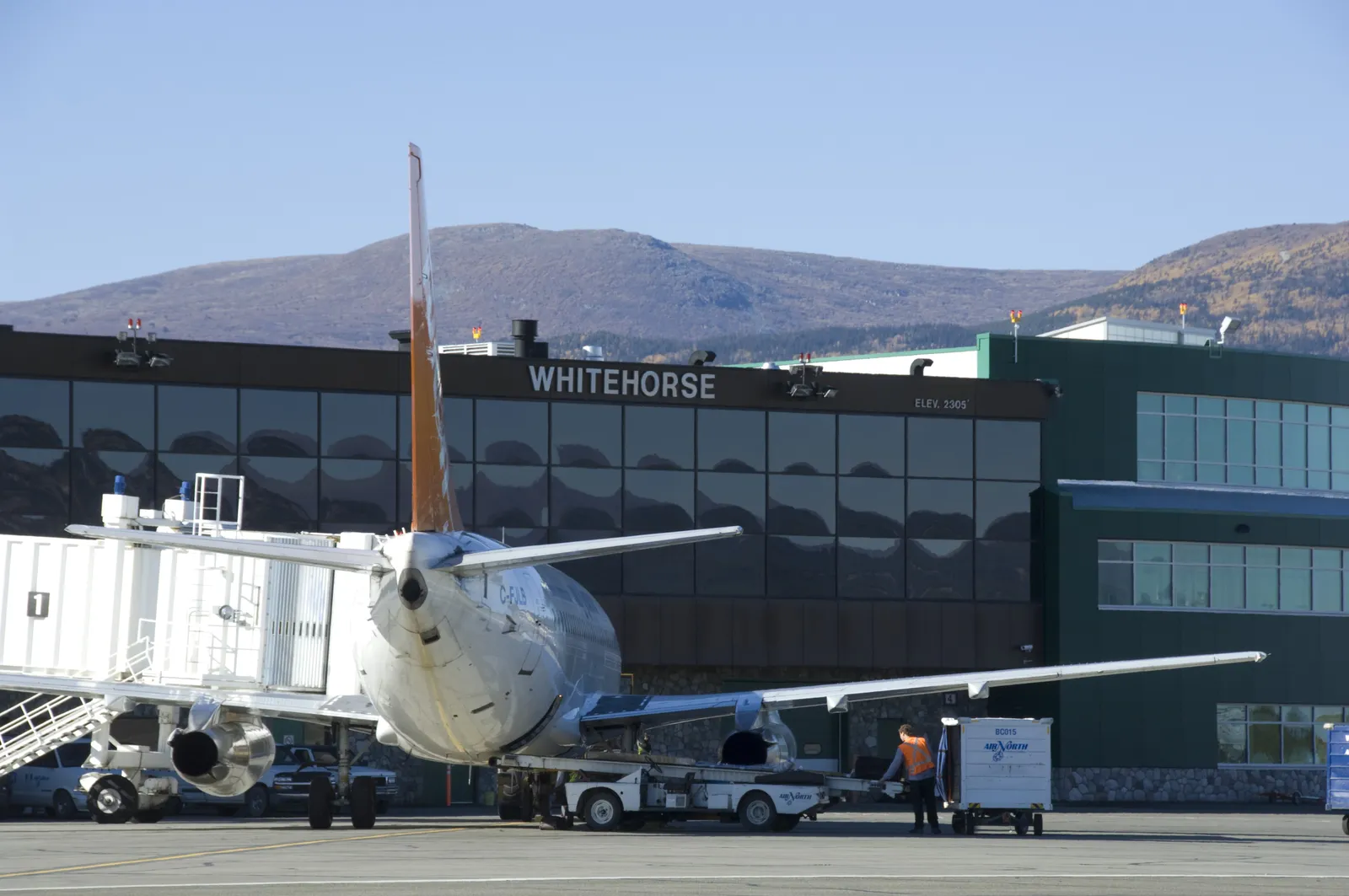 A plane docks outside of a landing space and terminal with the word &quot;Yukon&quot; in the front.