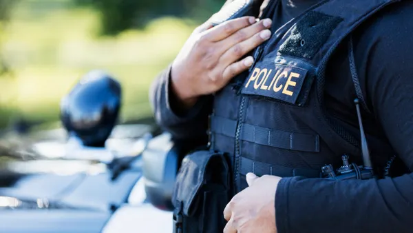 Cropped view of a person wearing a blue uniform that says "POLICE"