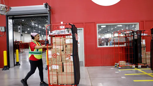 An employee moves a cart of packages at a Target sortation center.