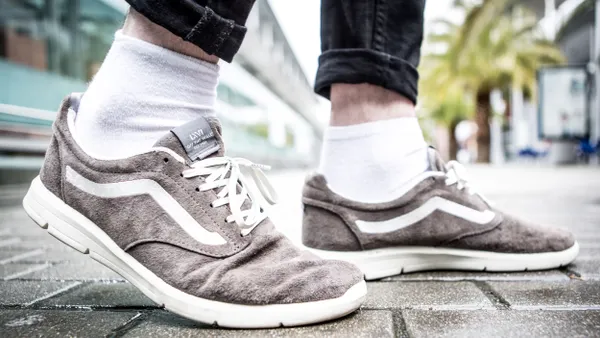 A closeup of a person's shoes, light grey Vans.
