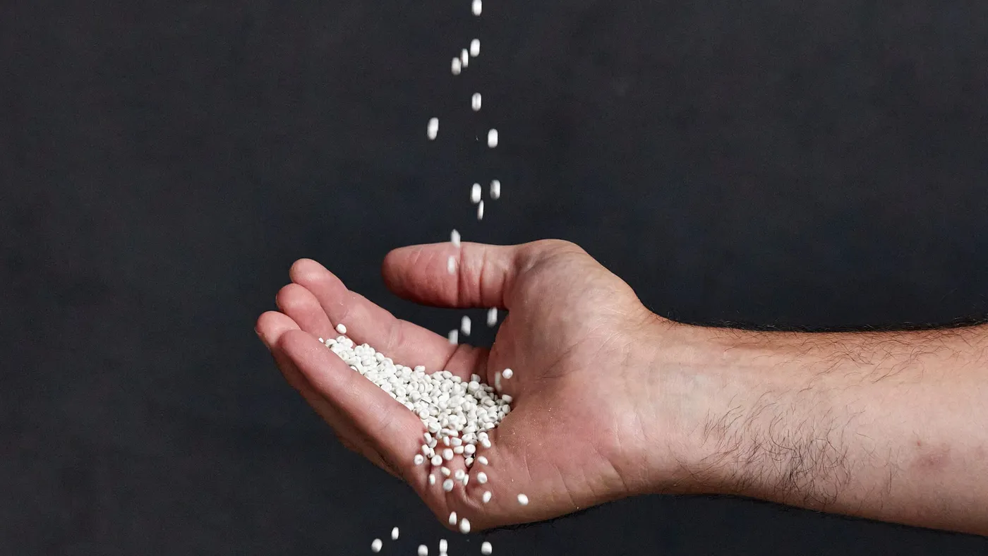 resin pellets fall into an outstretched hand