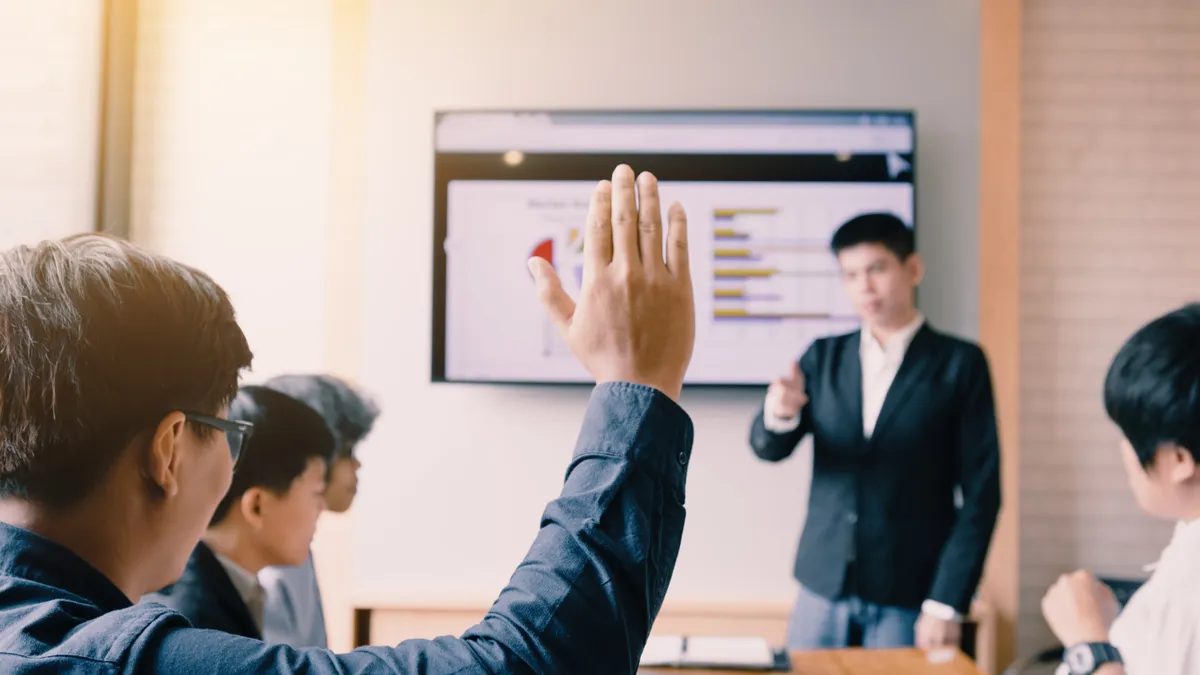 Man raises hand during a meeting.