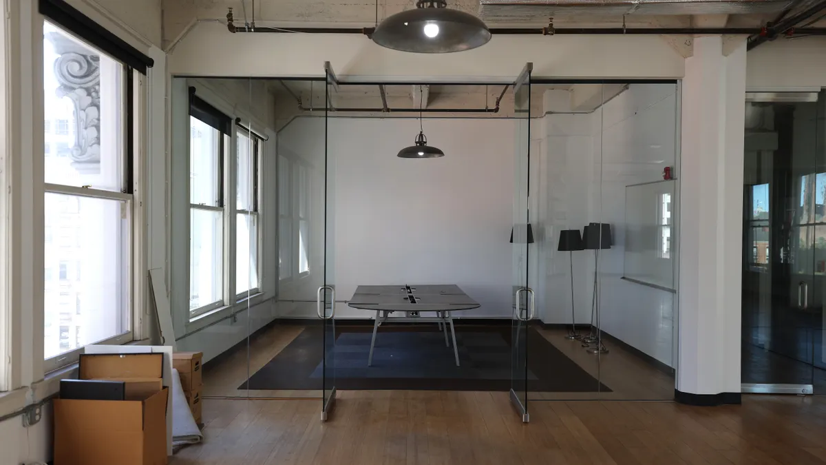 The interior of a vacant office with moving boxes stacked against one wall.