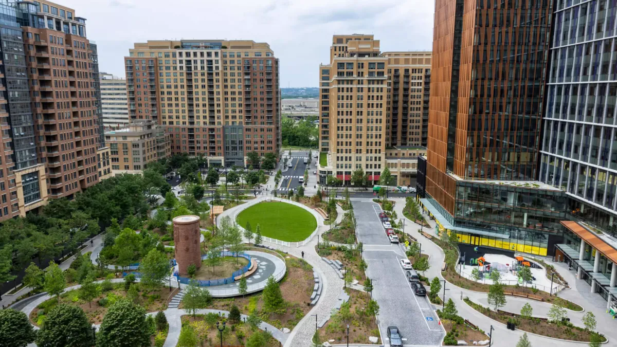 An aerial shot of a large park, with a new, glass-covered modern building along the right side. The park is well-maintained and green.