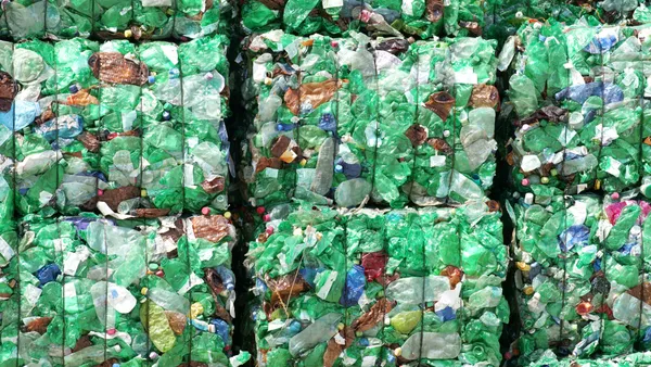 Bales of crushed plastic bottles, most of them green in hue.