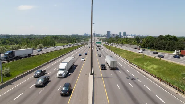 Part of Highway 401 with the Toronto skyline in the background during the day showing the blur of traffic on the road