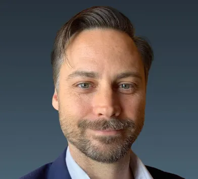 Headshot of a man with brown hair and a close trimmed beard and mustache.