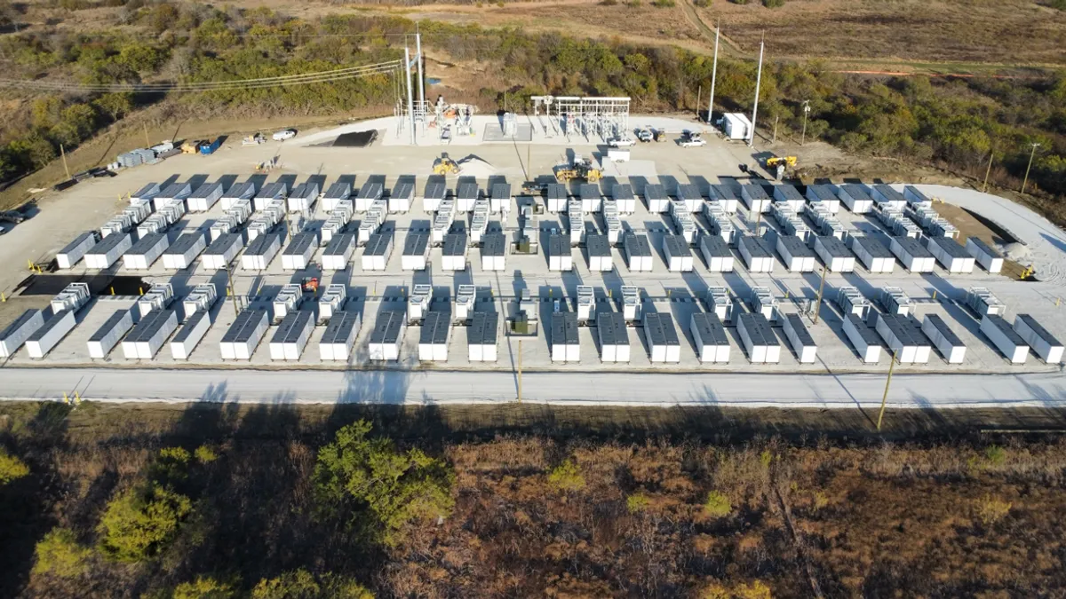 Rows of large containers with electric power lines in the background.