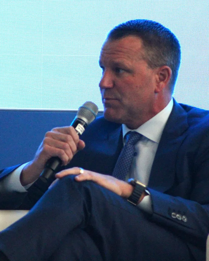 A person looks to the side while sitting in a white chair.
