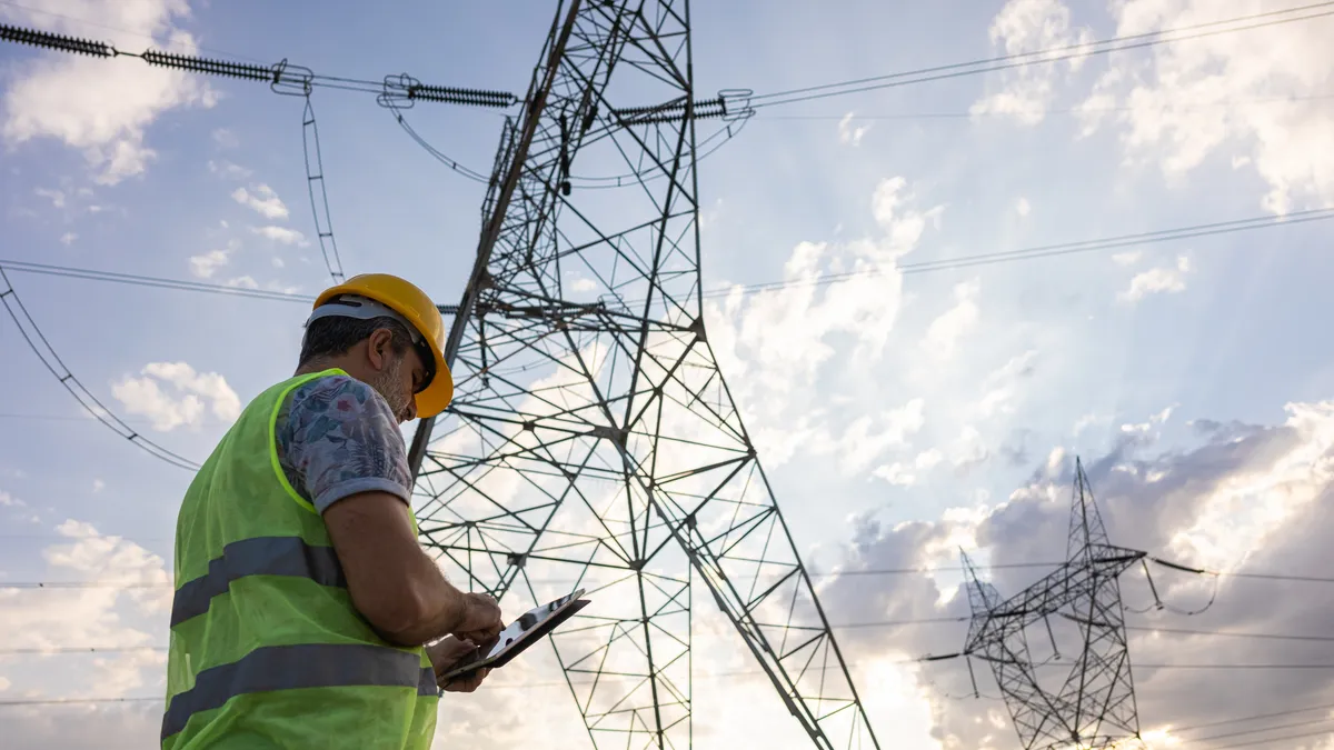 Engineers in front of power plant using digital tablet.