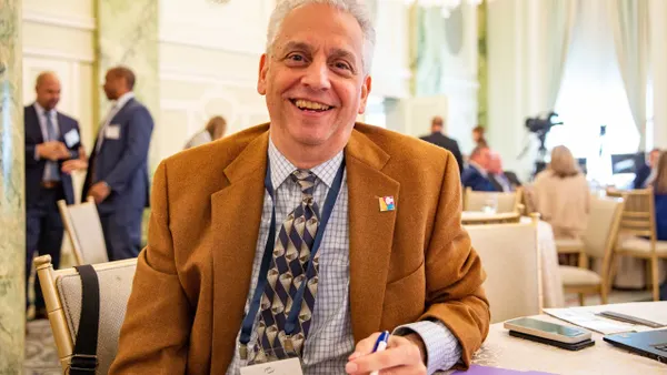 A man sitting at a conference table, smiles at the camera.