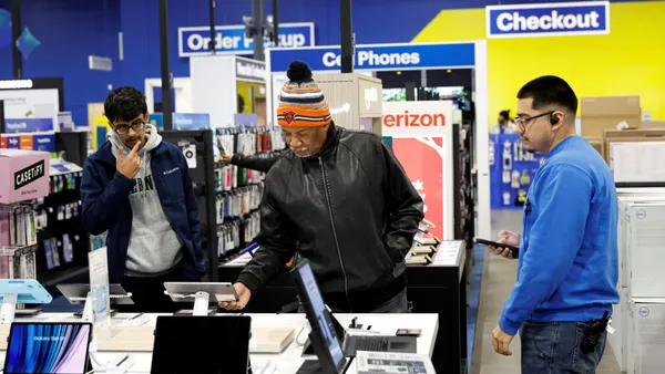Customers browse at a Best Buy, while an associate stands nearby ready to help.