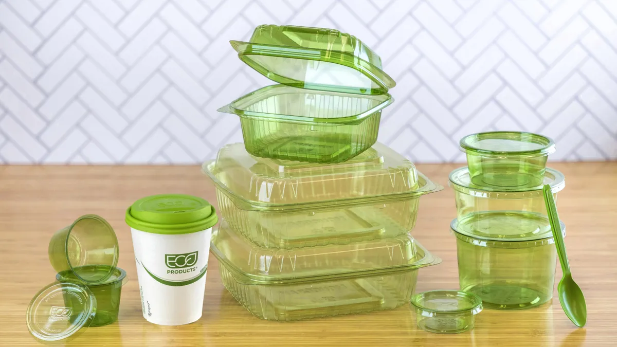 A variety of green-colored, translucent food service items including containers, cups and cutlery.