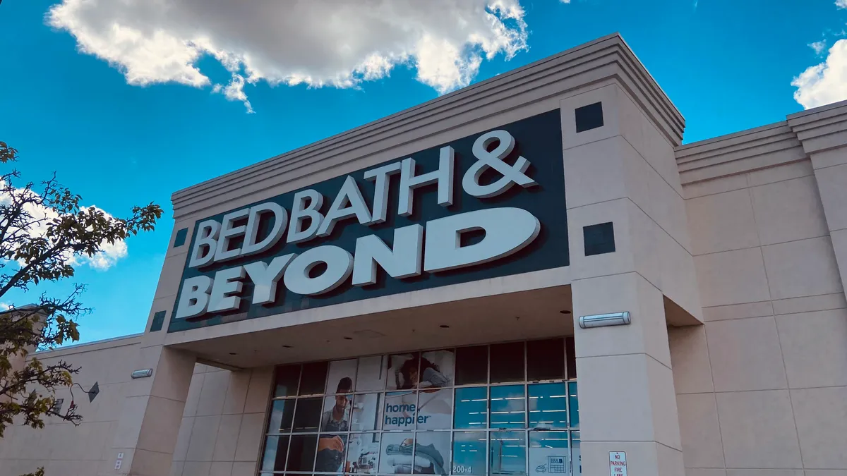 A Bed Bath & Beyond sign against a blue sky with puffy white clouds.