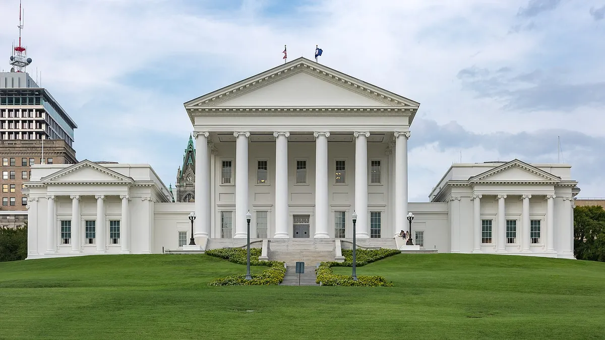 A large white building atop a green hill.