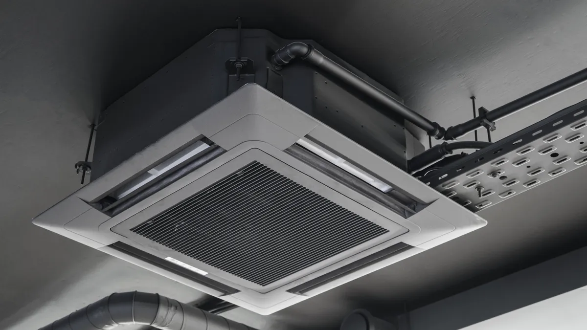 The indoor unit of an air conditioner featuring a cassette split system on a grey ceiling