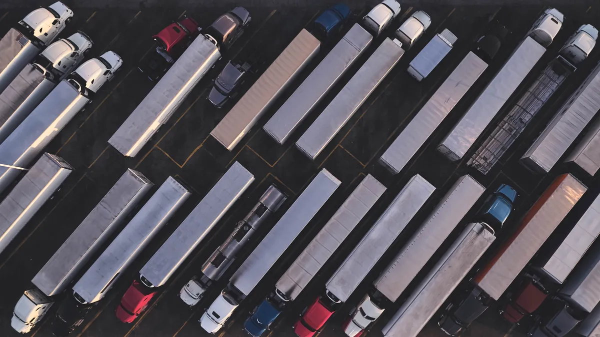 A drone captures an overhead view of trucks in a lot.