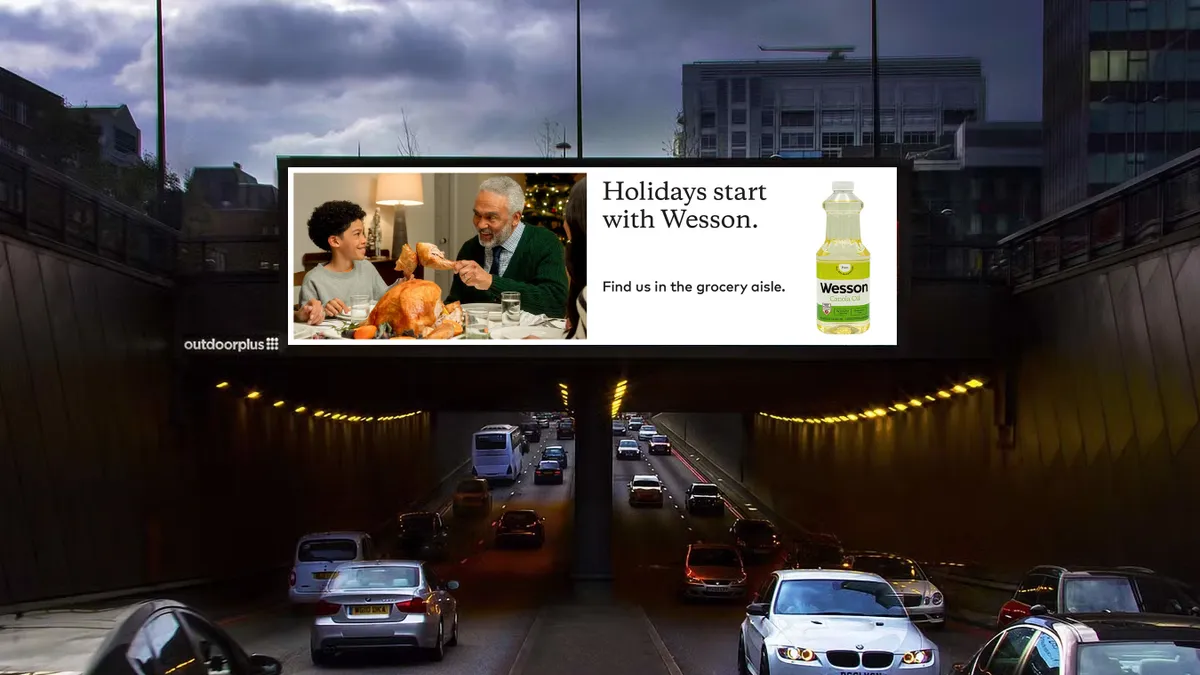 A billboard for Wesson Oil sits in the dark above a road.