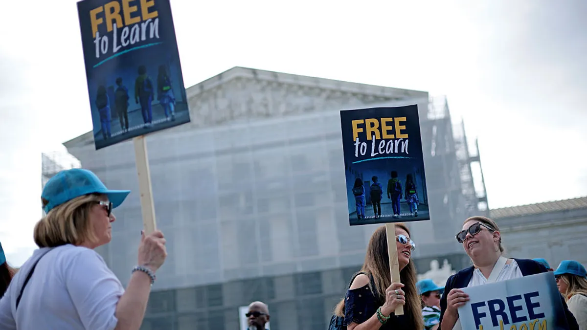 People are holding signs outside the U.S. Supreme Court building. The signs read "Free to learn"
